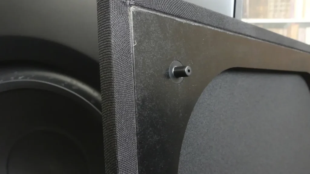 Close-up of the fabric grille and mounting pin for the Paradigm Defiance V12, demonstrating the build quality and secure attachment method.
