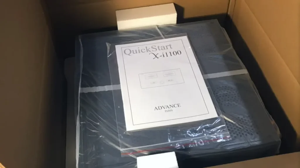 Advance Paris X-i1100 integrated amplifier unboxing showing the unit wrapped in protective plastic inside shipping box with QuickStart guide on top