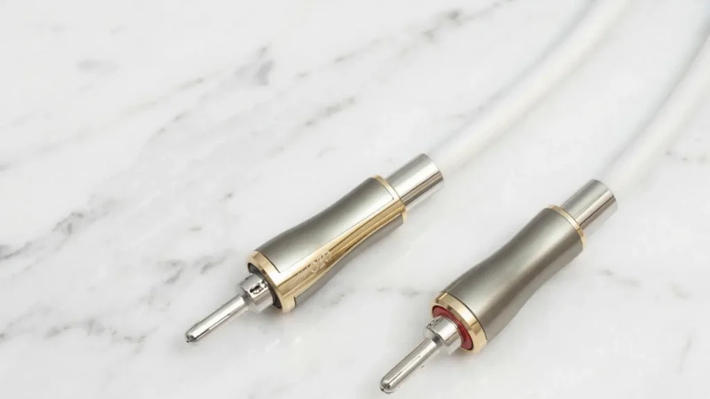 Close-up of QED Supremus Airloc rhodium-plated locking banana plugs with red and black channel indicators.