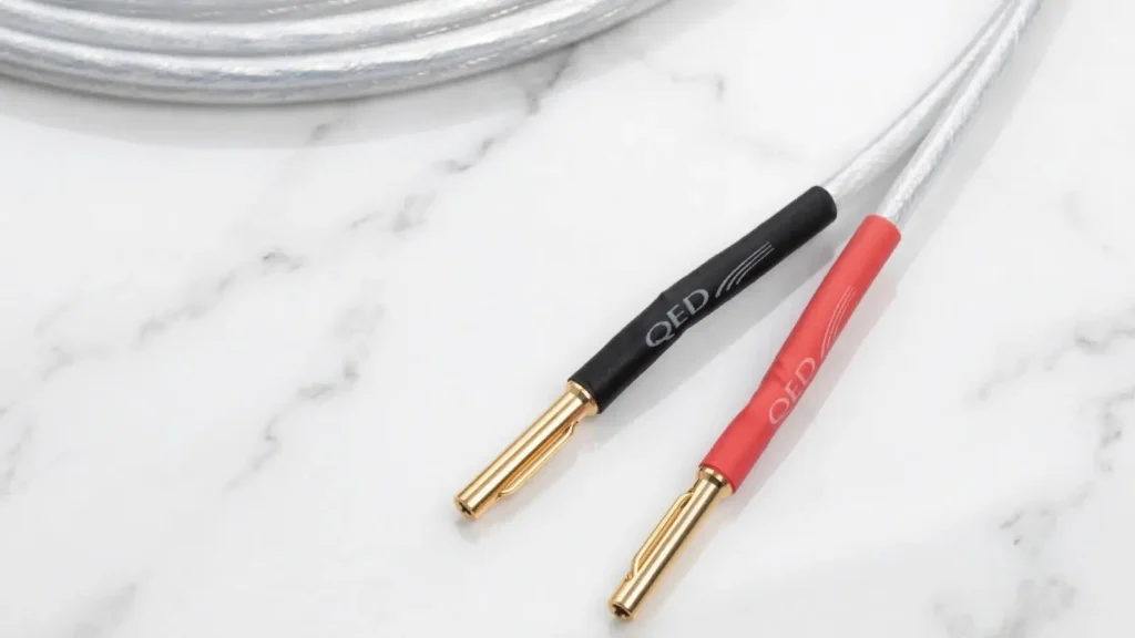 Close-up of the red and black heat-shrink termination on the QED XT25 speaker cable with spring-loaded banana pins.