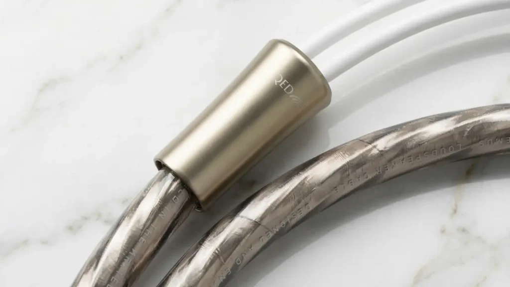 Detailed view of the thick QED Supremus cable showing the translucent jacket and the heavy-duty metal splitter with the QED logo