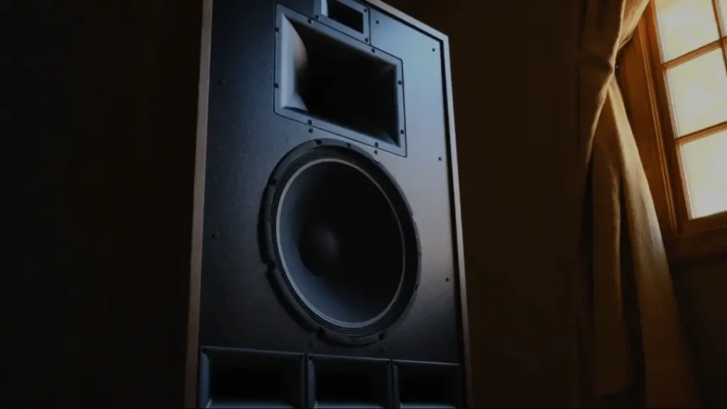 A Klipsch Cornwall IV speaker with its large 15-inch woofer and horn drivers, shown in a moodily lit listening room