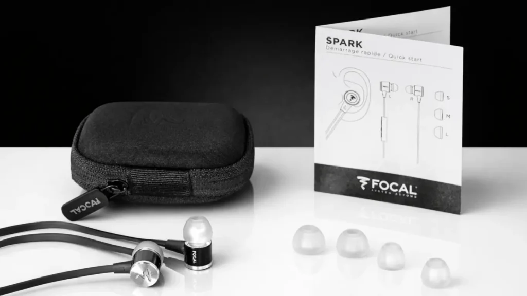 Focal Spark Black in-ear headphones displayed with retail box, open packaging, earbuds, remote control, and carrying case