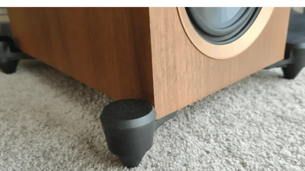 Base of the MartinLogan F1 in walnut finish, featuring the outrigger-style aluminum feet and a 5.5-inch aluminum woofer with a decorative surround.