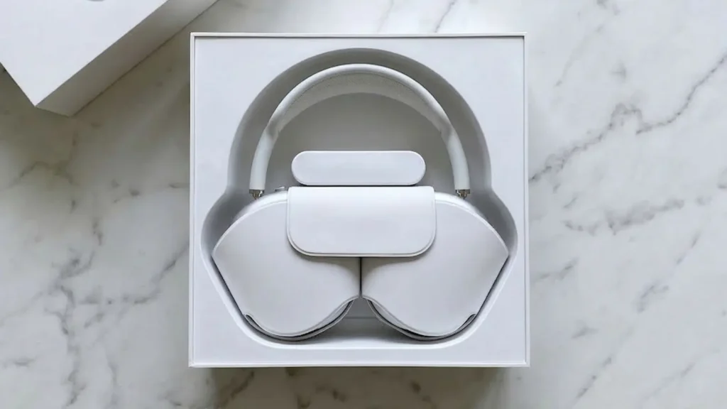 AirPods Max 2 unboxing, headphones nestled in their white Apple packaging box, top-down view