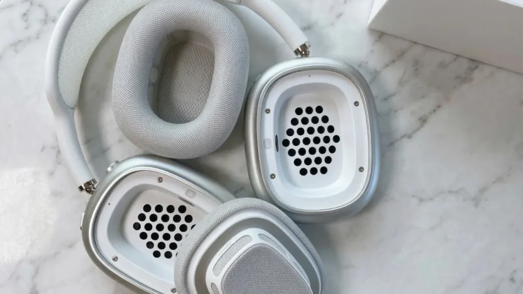 AirPods Max 2 with magnetic ear cushions removed, revealing the internal driver grille and acoustic port holes on the aluminum ear cup housing